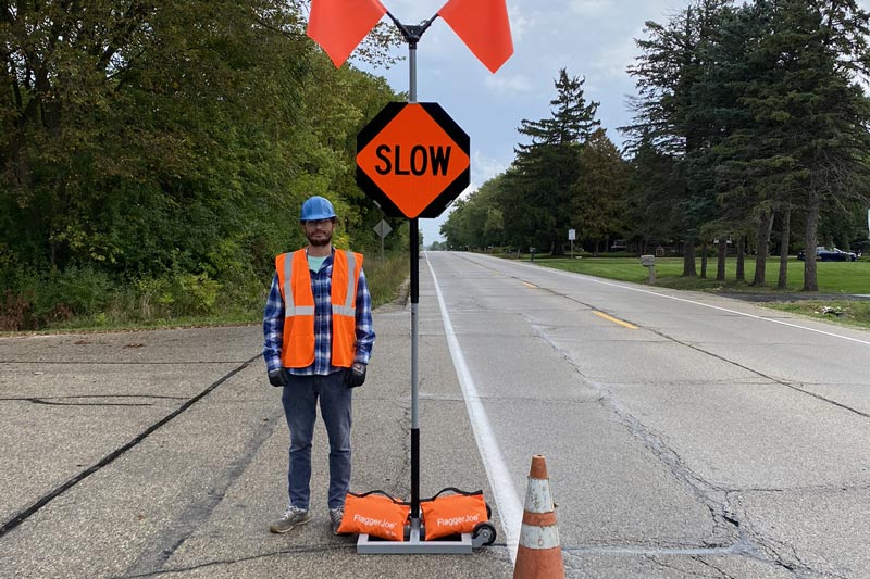 Flagger standing on street with FlaggerJoe Platinum safety sign system